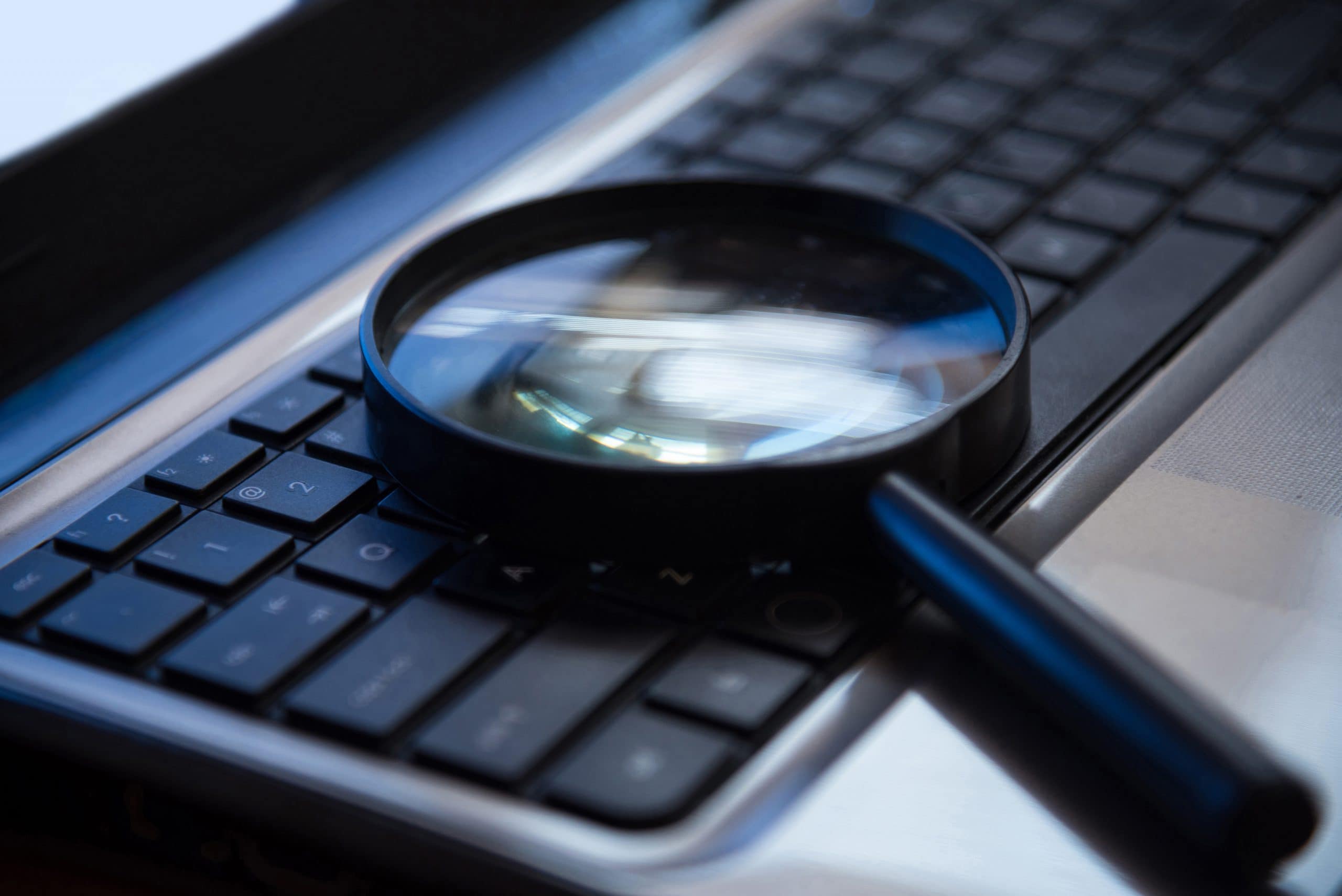 Selective focus on keyboard with magnifier searching concept in dark low key night tone