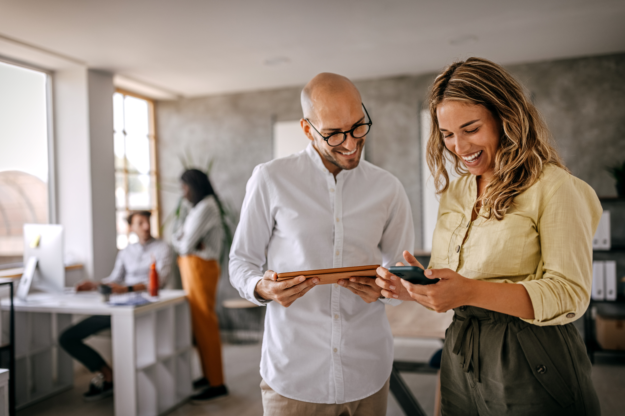 Businessman and businesswoman smiling looking at phone