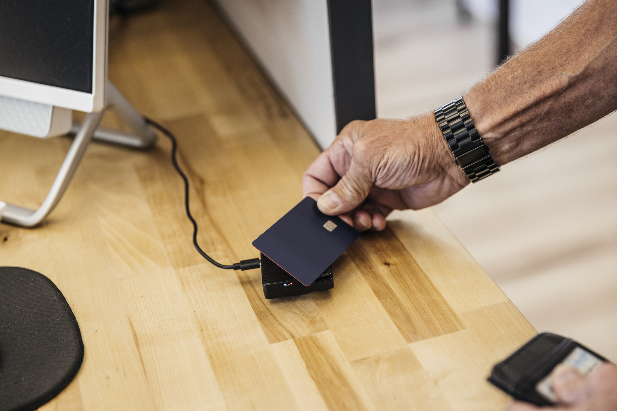 Cropped hand of senior man paying through credit card at reception desk